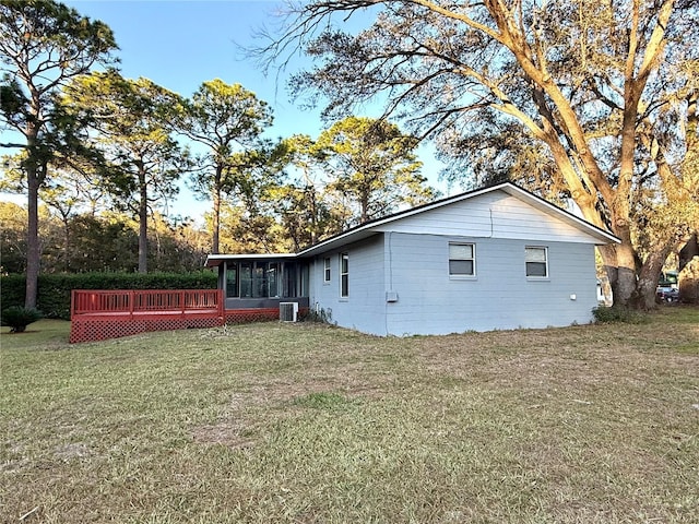 view of property exterior with a sunroom, a deck, central AC unit, and a lawn