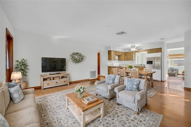 living room with light wood-type flooring, ceiling fan, and sink