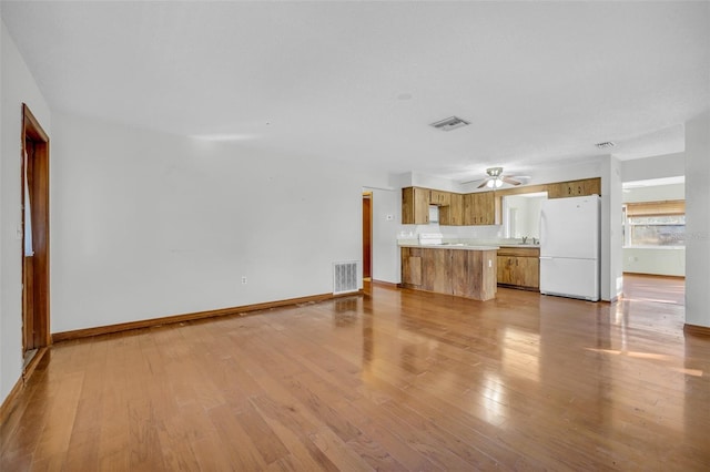 unfurnished living room featuring ceiling fan, sink, and light hardwood / wood-style floors