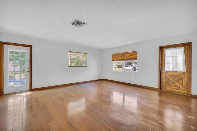 unfurnished living room featuring light hardwood / wood-style flooring and a textured ceiling