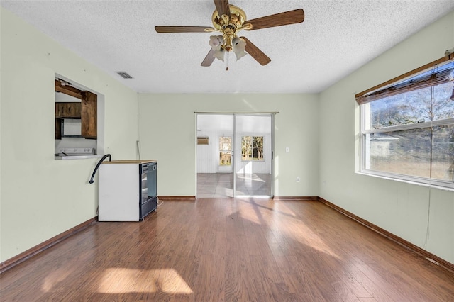 unfurnished living room with ceiling fan, a textured ceiling, and hardwood / wood-style flooring