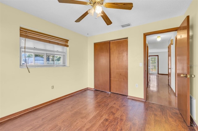 unfurnished bedroom featuring ceiling fan, dark hardwood / wood-style flooring, and multiple windows