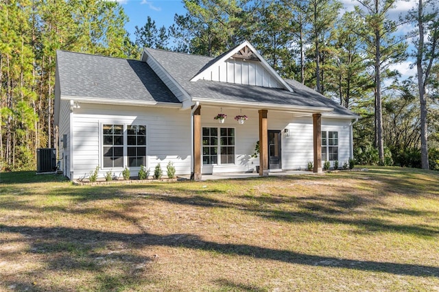 view of front of home with cooling unit, covered porch, and a front yard