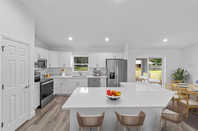 kitchen featuring sink, a breakfast bar area, a kitchen island, white cabinetry, and stainless steel appliances