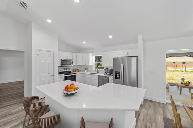 kitchen featuring white cabinets, light wood-type flooring, stainless steel appliances, and a healthy amount of sunlight