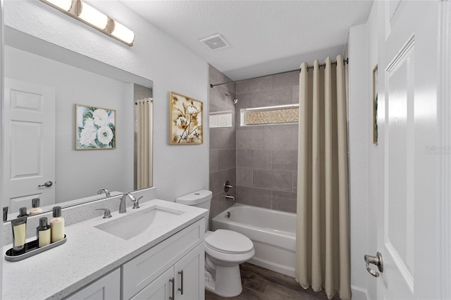 full bathroom featuring vanity, toilet, a textured ceiling, wood-type flooring, and shower / tub combo