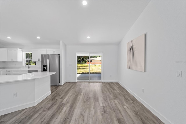 kitchen with sink, white cabinetry, stainless steel refrigerator with ice dispenser, and light wood-type flooring