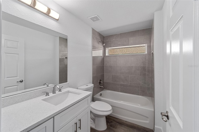 full bathroom with vanity, a textured ceiling, hardwood / wood-style floors, toilet, and tiled shower / bath