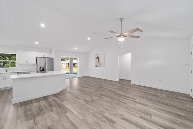 unfurnished living room with ceiling fan, sink, lofted ceiling, and light wood-type flooring