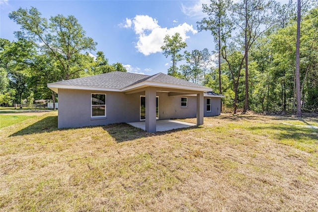 rear view of property featuring a lawn and a patio area