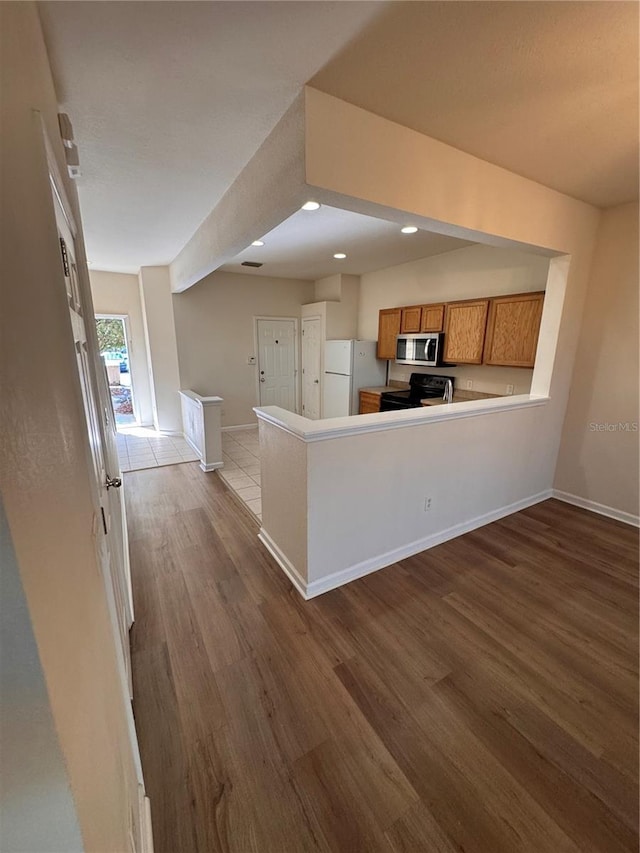 kitchen featuring white refrigerator, light hardwood / wood-style flooring, kitchen peninsula, and black range with electric stovetop