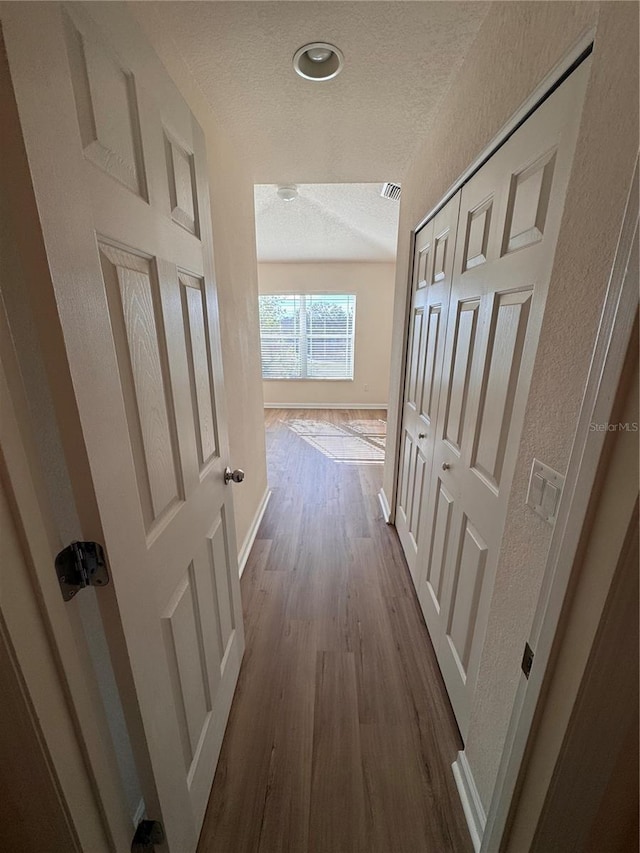 corridor with wood-type flooring and a textured ceiling