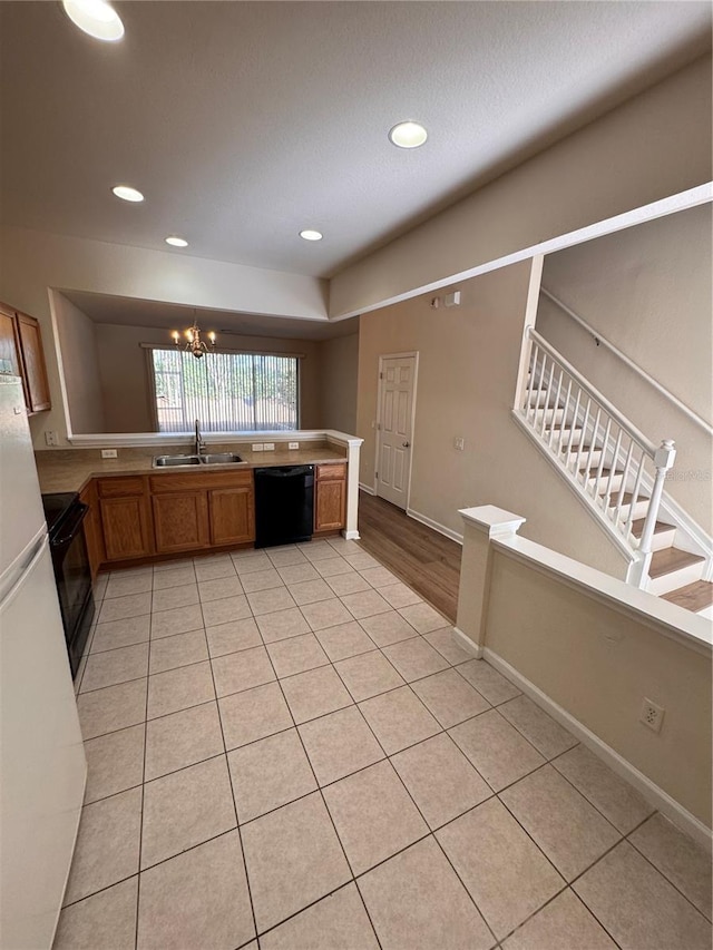 kitchen featuring black appliances, light tile patterned floors, sink, and a chandelier