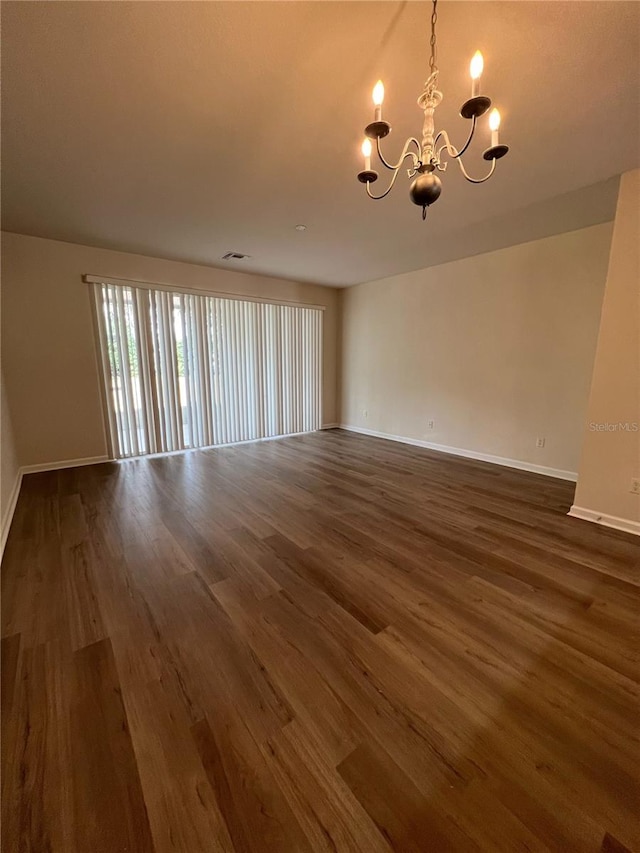 empty room with an inviting chandelier and dark hardwood / wood-style flooring