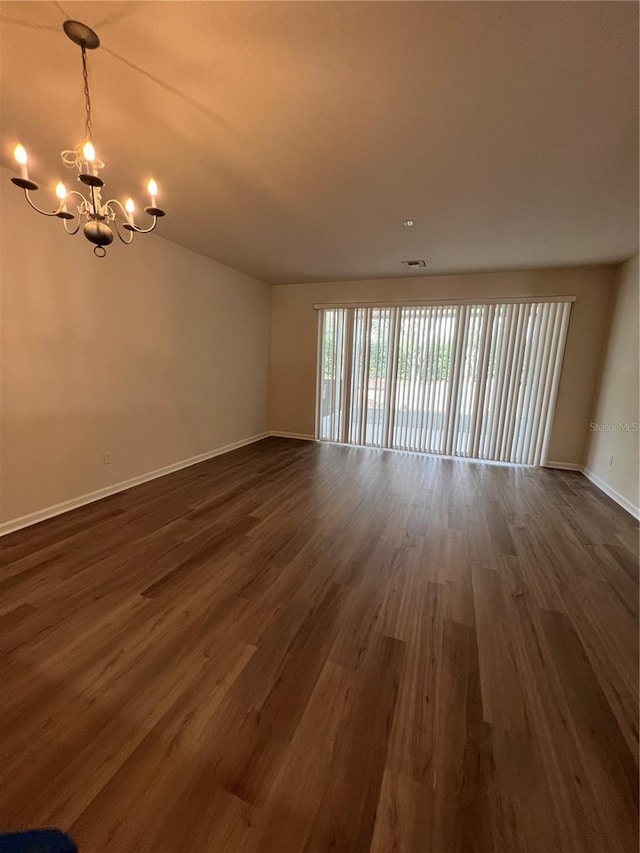 unfurnished room with dark wood-type flooring and a chandelier