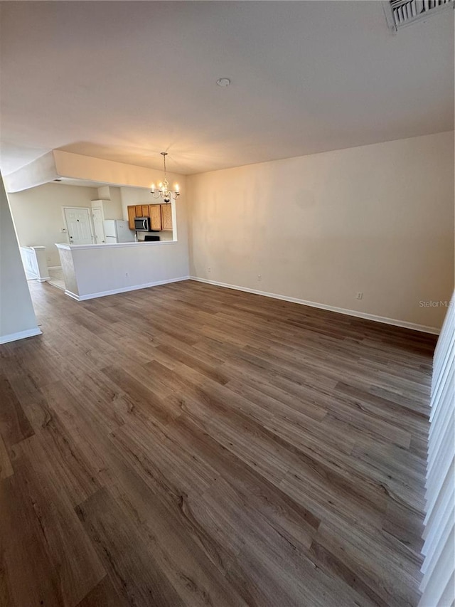 unfurnished living room featuring dark hardwood / wood-style floors and an inviting chandelier