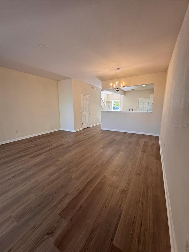 unfurnished living room with dark hardwood / wood-style flooring and a notable chandelier