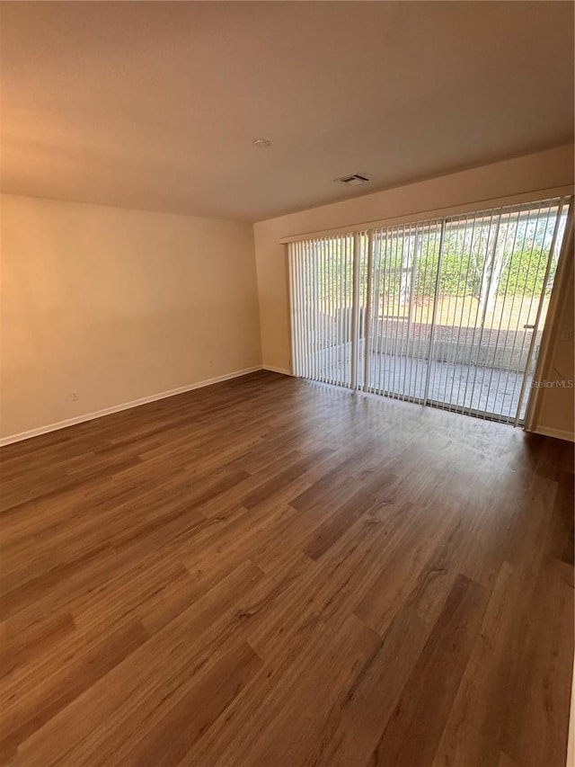 empty room with a healthy amount of sunlight and dark hardwood / wood-style flooring