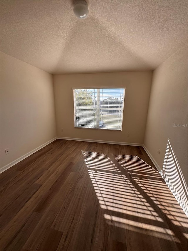 spare room featuring a textured ceiling and dark hardwood / wood-style floors