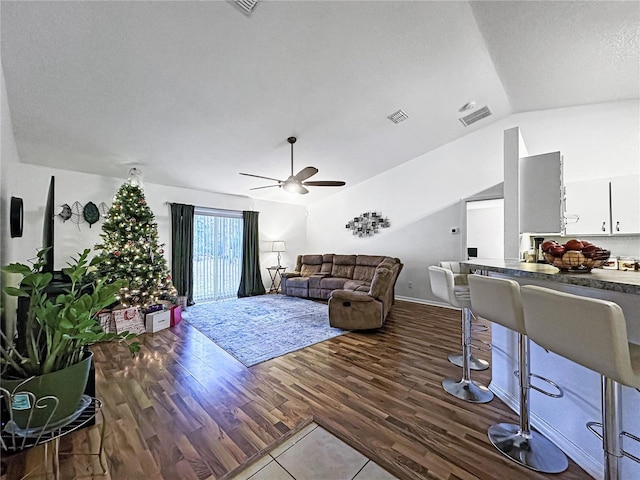 living room featuring a textured ceiling, ceiling fan, dark hardwood / wood-style floors, and lofted ceiling