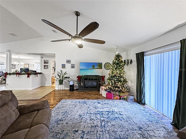 living room with hardwood / wood-style floors, ceiling fan with notable chandelier, and lofted ceiling