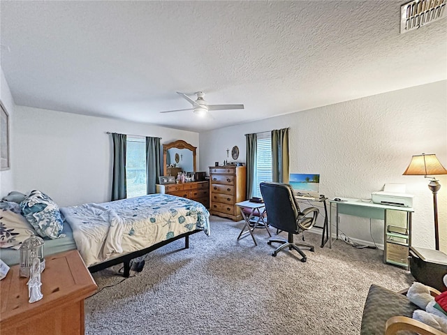 carpeted bedroom with multiple windows, a textured ceiling, and ceiling fan