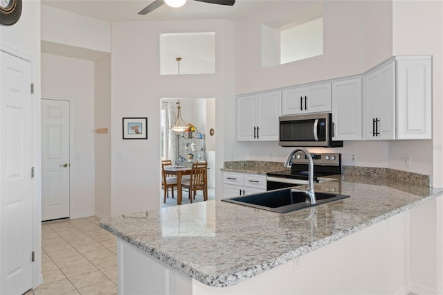 kitchen with kitchen peninsula, light tile patterned floors, stainless steel appliances, and white cabinets