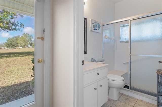 bathroom with tile patterned floors, a shower with door, vanity, and toilet