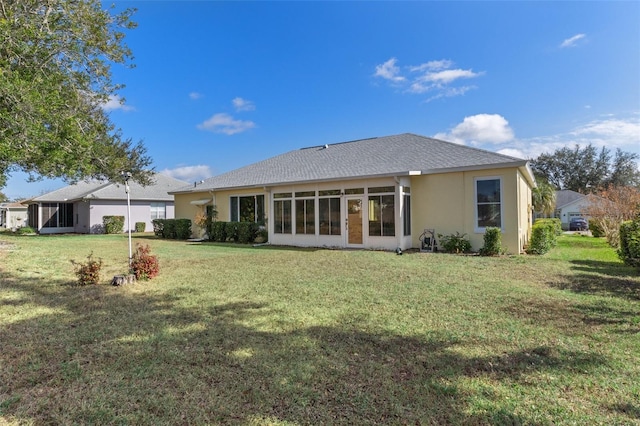 rear view of property with a lawn and a sunroom