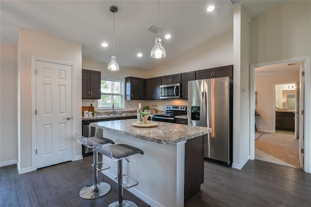 kitchen featuring dark brown cabinetry, stainless steel appliances, pendant lighting, vaulted ceiling, and a kitchen island