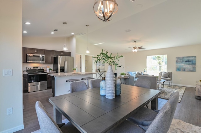 dining area with ceiling fan with notable chandelier, dark hardwood / wood-style flooring, and lofted ceiling