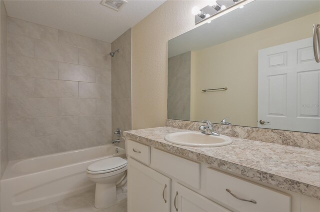 full bathroom featuring tile patterned flooring, vanity, tiled shower / bath combo, and toilet