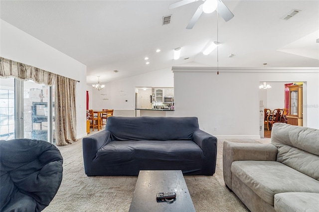 carpeted living room with ceiling fan with notable chandelier and lofted ceiling