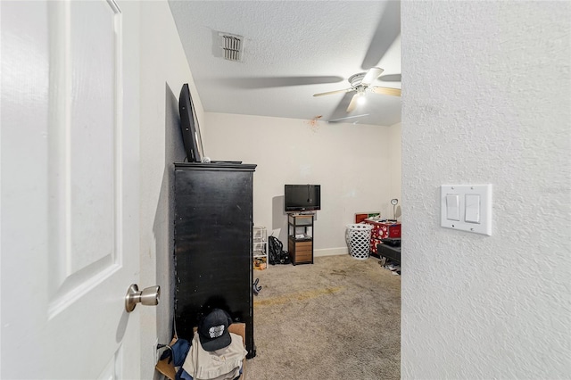 bedroom with ceiling fan, carpet floors, and a textured ceiling