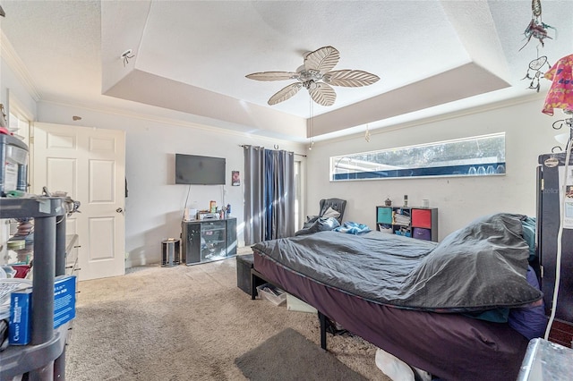 bedroom with carpet flooring, a textured ceiling, a raised ceiling, and ceiling fan