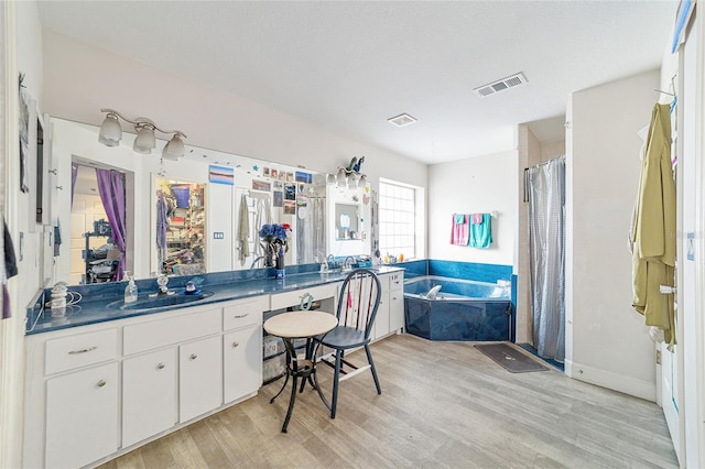 bathroom with hardwood / wood-style floors, vanity, shower with separate bathtub, and a textured ceiling