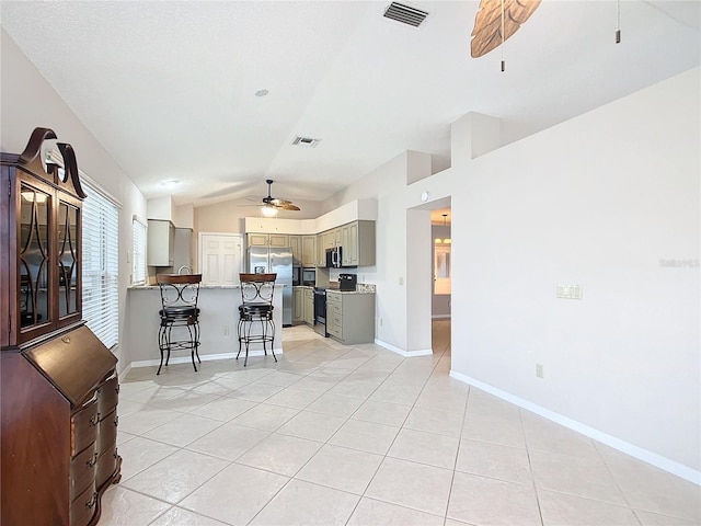 kitchen featuring gray cabinetry, a breakfast bar, light tile patterned flooring, and stainless steel appliances