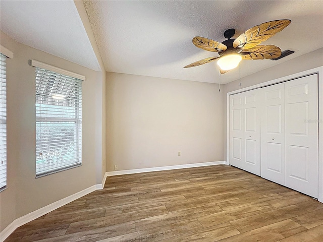 unfurnished bedroom with ceiling fan, a closet, wood-type flooring, and a textured ceiling