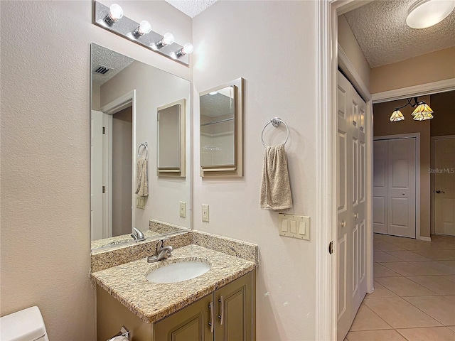 bathroom with tile patterned floors, vanity, toilet, and a textured ceiling