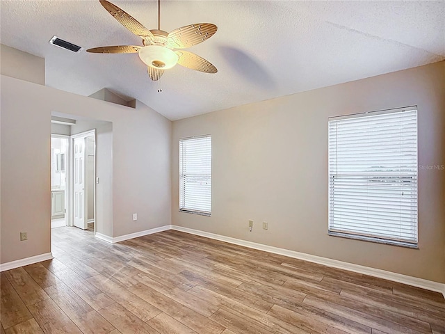 spare room featuring a textured ceiling, ceiling fan, light hardwood / wood-style floors, and vaulted ceiling