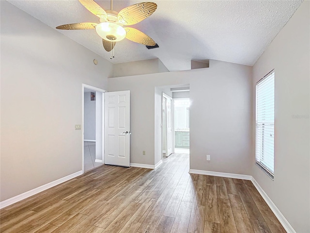 spare room featuring vaulted ceiling, ceiling fan, light hardwood / wood-style flooring, and a textured ceiling