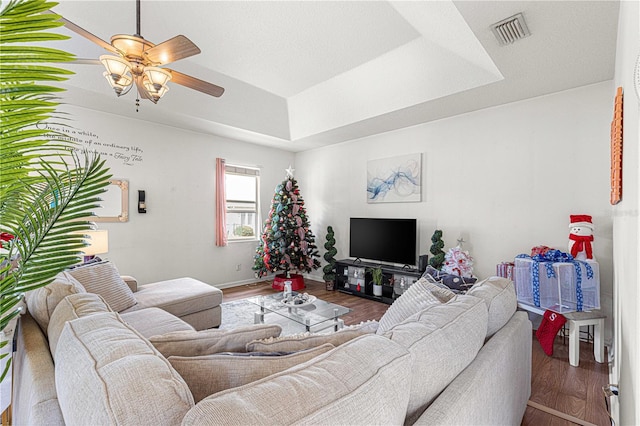 living room with hardwood / wood-style floors, a tray ceiling, and ceiling fan