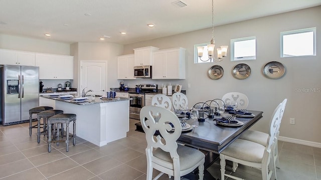 tiled dining space featuring a chandelier and sink