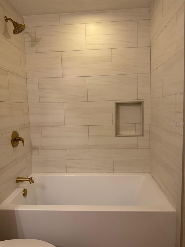 bathroom featuring toilet and tiled shower / bath