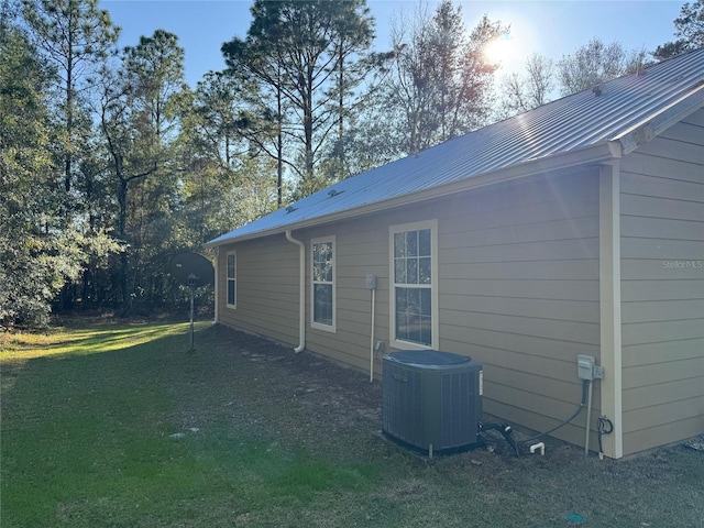 view of side of property featuring a lawn and central air condition unit