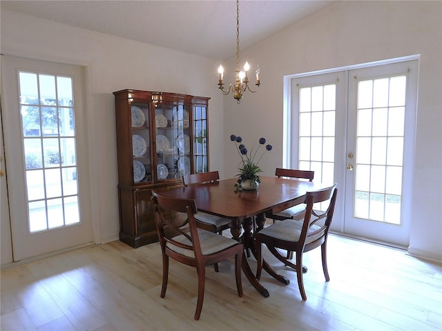 dining space with french doors, vaulted ceiling, light hardwood / wood-style floors, and an inviting chandelier