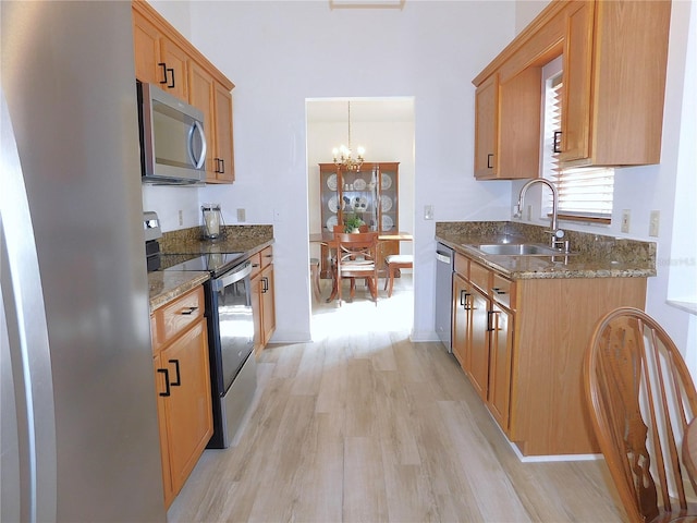 kitchen featuring sink, hanging light fixtures, light wood-type flooring, stainless steel appliances, and a chandelier