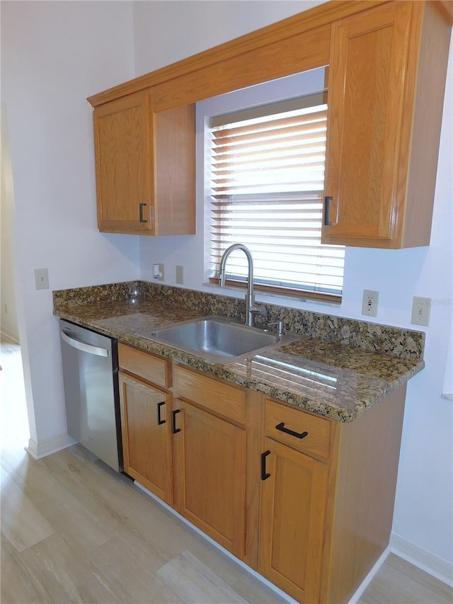 kitchen with dishwasher, dark stone countertops, and sink