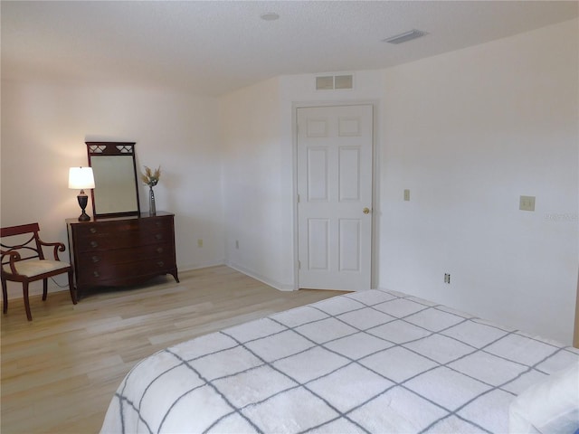 bedroom with light hardwood / wood-style flooring and a textured ceiling