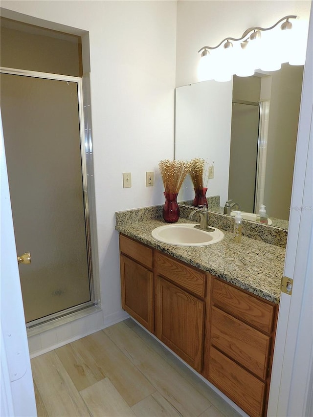 bathroom with hardwood / wood-style floors, vanity, and a shower with shower door